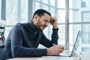 Stressed man working on laptop.